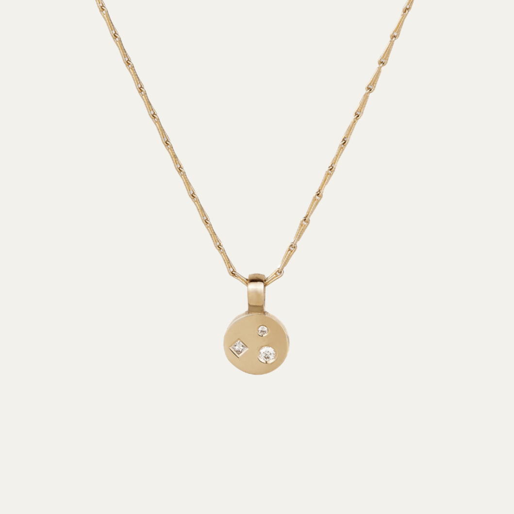 Gold necklace with a round pendant featuring three small diamonds 