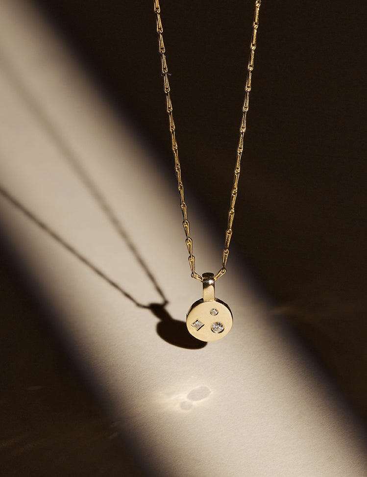 9ct solid yellow gold and 18ct solid yellow gold diamond disc pendant necklace in a spotlight