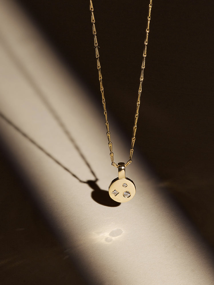 9ct solid yellow gold and 18ct solid yellow gold diamond disc pendant necklace in a spotlight