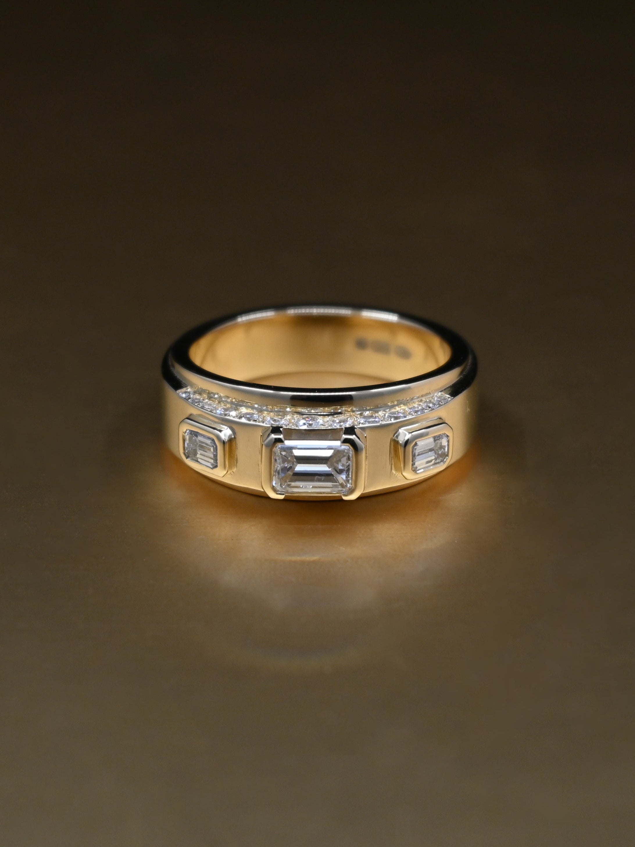 Gold ring with embedded diamonds on a reflective surface