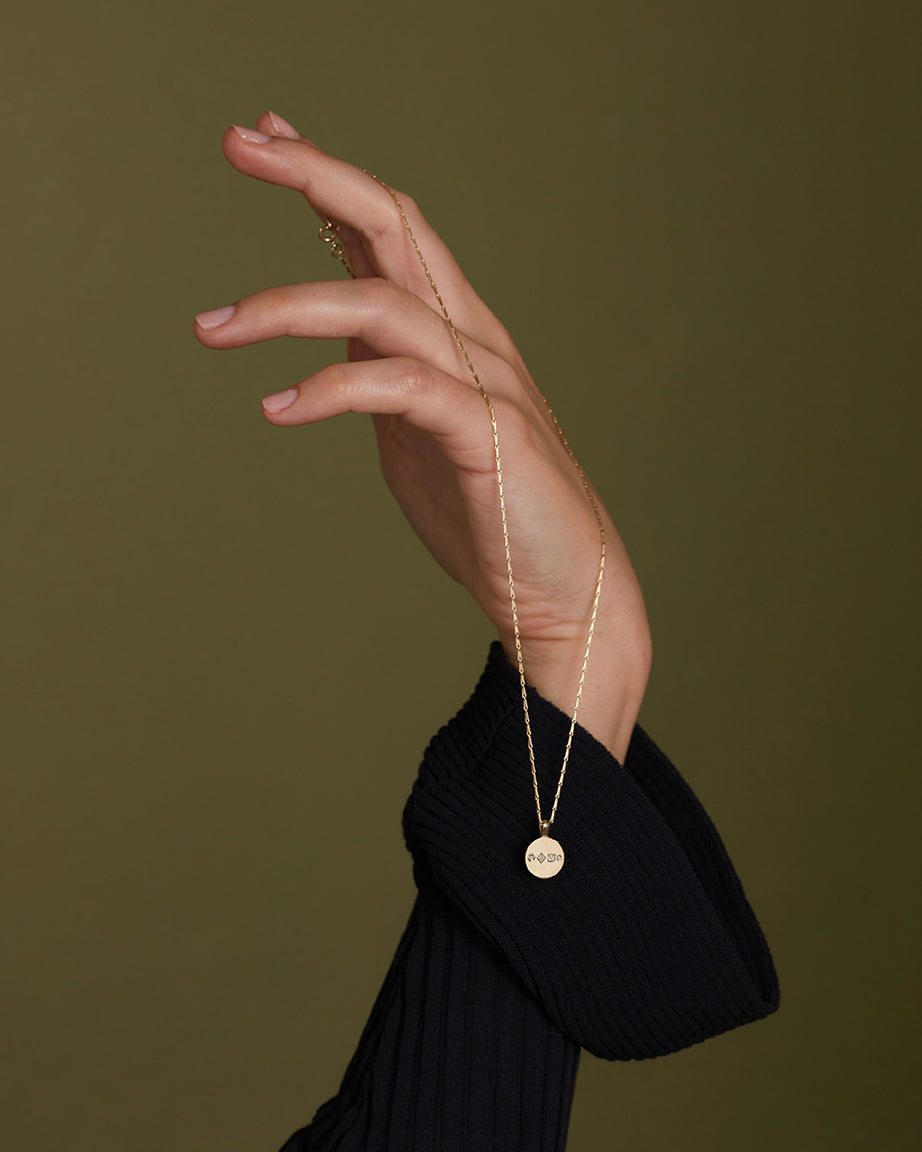 9ct solid yellow gold and 18ct solid yellow gold diamond disc pendant necklace hanging on a hand