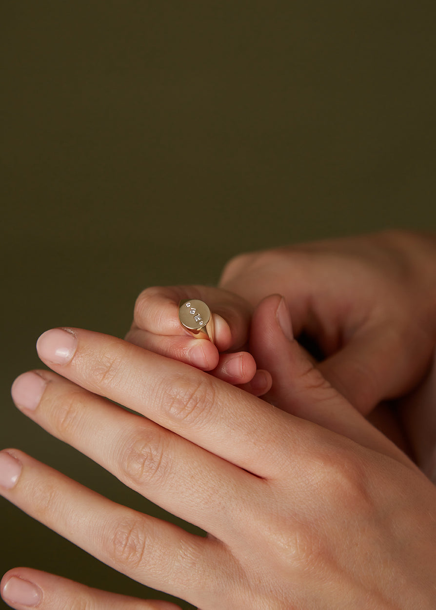 Hands holiding a 9ct solid yellow gold and 18ct solid yellow gold women's diamond signet ring